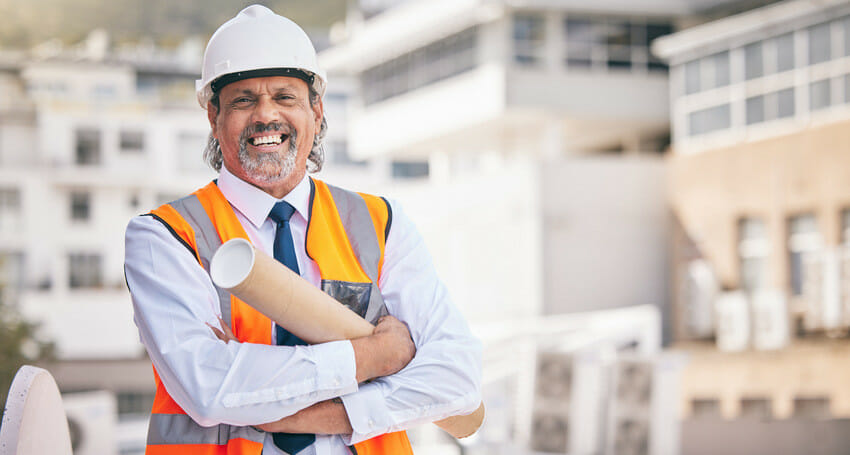 A smiling civil engineer holding a piece of paper.
