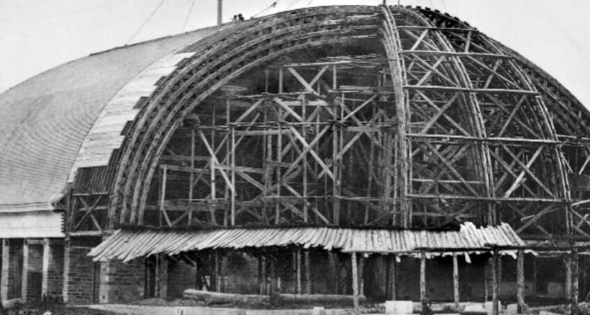 A large domed structure under construction, with exposed wooden scaffolding and partial roofing visible.
